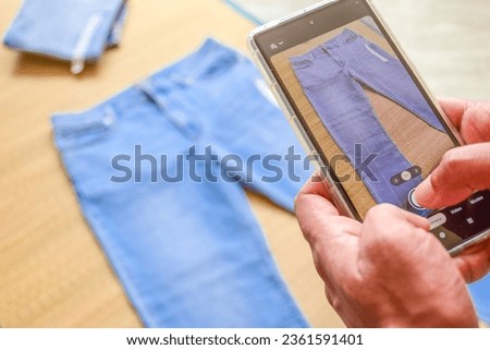 Woman taking picture of blue jeans on korai grass mat background. Preparation for livestream selling online or vlogging. 