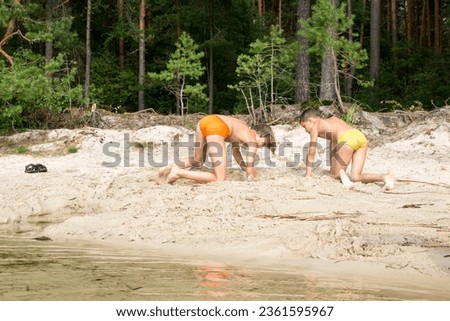 Family holiday in nature, children playing in the sand on the shore of the lake.