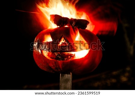 Halloween pumpkin fire smile and scary eyes for party night. Close up view of scary Halloween pumpkin with fire eyes at black background. Soft focus