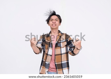 A funny young asian man powering up with his thin lanky body, pretending to be an anime character. Example of an otaku or wrestling fan. Isolated on a white background.