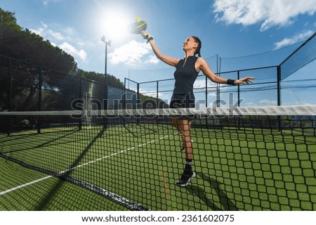 Padel tennis player with racket in action on the court. Woman athlete with paddle racket on court outdoors. Sport concept. Download a high quality photo for the design of a sports app or web site.