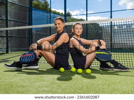 Family leisure and sports hobby. Two padel tennis players with rackets. Woman coach and girl teenager athlete with paddle racket on court outdoors. Sport concept. Royalty-Free Stock Photo #2361602087