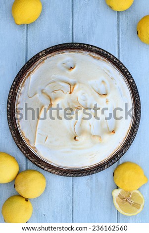 Lemon Meringue Pie with fresh lemons over a beautiful blue wooden background.
