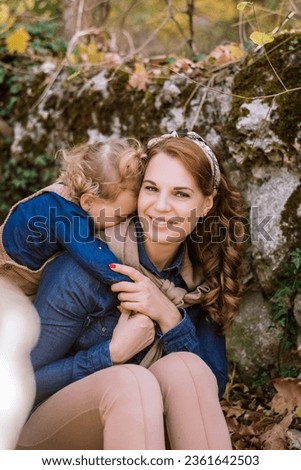 Happy mother 28-35 years old hugging her daughter toddler 1-2 years old. Family, happy childhood, stylish family street look, hugs of people. Concept: family and love. Selective focus on mom's face Royalty-Free Stock Photo #2361642503