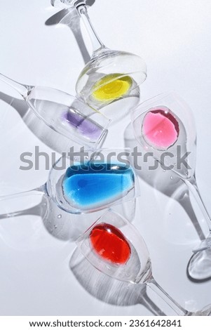 the shadow of a glass filled with colorful water on a white background
