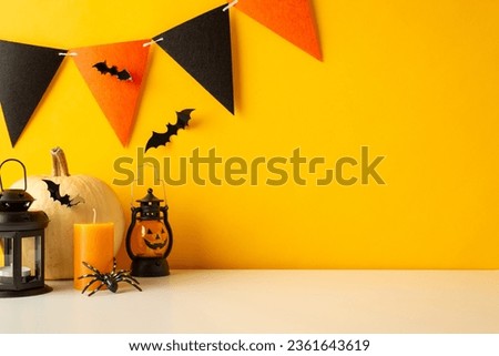 Transform your table for Halloween festivities. Side view shot of tabletop filled with themed decorations, pumpkin, jack-o'-lantern lamp, bats, spider, candle, festive garland on yellow wall backdrop