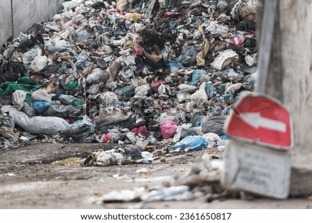 Landfill site, a pile of stinky different junk disposal in the concrete section for unsorted waste materials Royalty-Free Stock Photo #2361650817