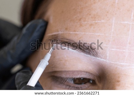 Detailed view of a professional conducting eyebrow mapping on a woman for permanent makeup