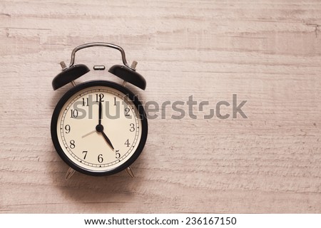 alarm clock showing five o'clock on wooden background Royalty-Free Stock Photo #236167150