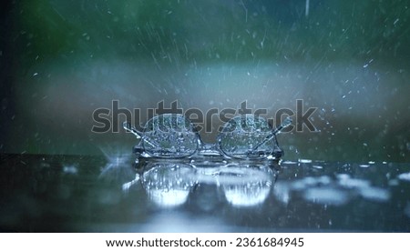 A kid's glasses or specs placed in rain with splashed rain droplets.                  