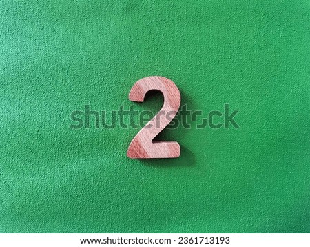 wooden number two , selective focus number green background . Top view isolated photo.