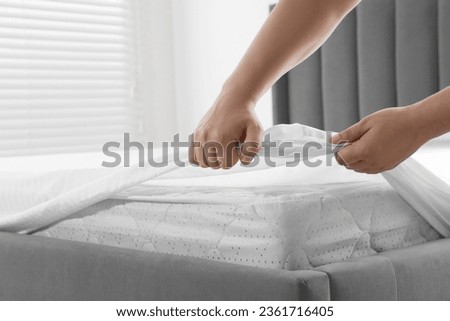 Woman covering mattress with protector indoors, closeup Royalty-Free Stock Photo #2361716405