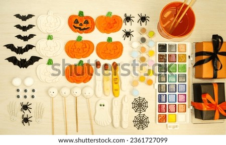 On the table there are crafts made from salt dough, pumpkins, monsters, witch fingers, ghosts, paints, gift boxes, and Halloween attributes.  Preparing for Halloween.  Children's crafts concept.