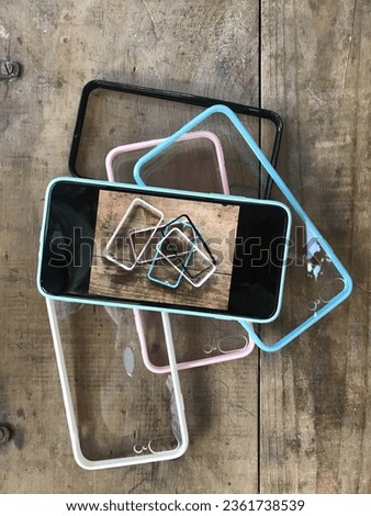 Transparent mobile phone cases on a wooden background, light blue case, pink case, black case and white case