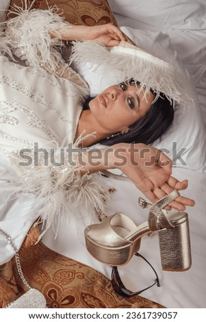A bride in a beautiful gown reclines on a hotel bed, creating a serene portrait of elegance and femininity.