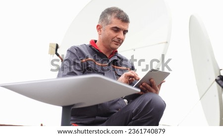 A man installs a satellite dish for fast Internet. Royalty-Free Stock Photo #2361740879