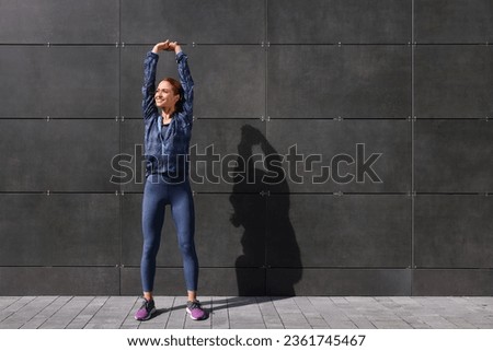 Beautiful woman in gym clothes doing exercises on street, space for text Royalty-Free Stock Photo #2361745467