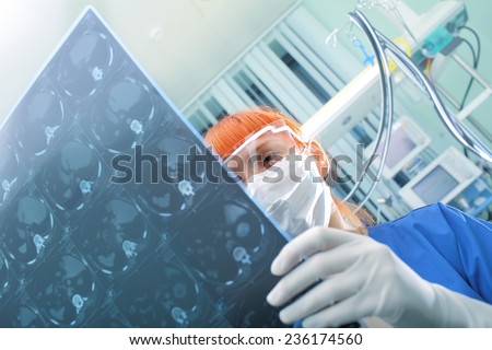 Female doctor with glasses and mask inspects CT picture