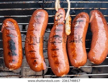 Sausages on the grill with barbecue briquettes smoke in nature