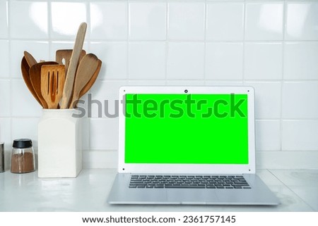 Mockup of laptop computer with empty green screen sugar, spices in glass jars eggs, vegetable,tomato and a whisk on the kitchen on white table. Flat lay. Concept of food preparation, on background.