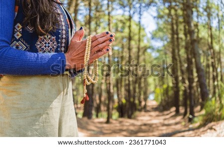 Close up of clasping hands holding a japa mala.  Copy space