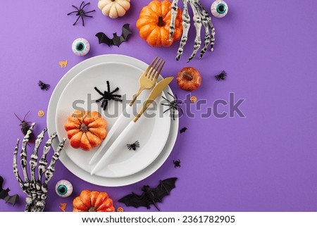 Conjuring a captivating Halloween tabletop decor. Top view photo of plates, cutlery, skeleton hands, colorful pumpkins, eyeballs, scary insects on purple background with ad spot Royalty-Free Stock Photo #2361782905