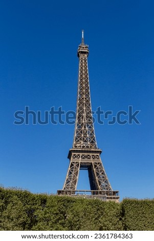 Daytime view of the exterior architecture of the Eiffel Tower in Paris, with blue sky background