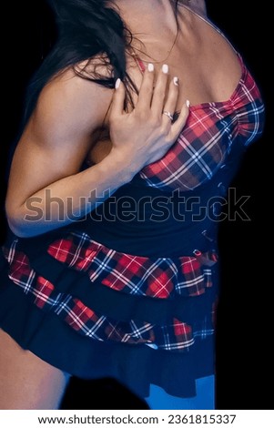 Women's light erotica in a dark dress in a red check with a hand at the chest. Royalty-Free Stock Photo #2361815337