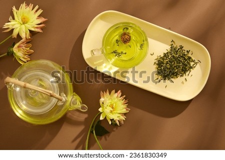 Tea concept with white tea set of transparent cup and teapot decorated with fresh flowers on the brown background. Mid Autumn Festival minimalist design