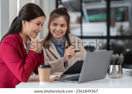 team work process Two asian businesswoman working with laptop computer and discussing documents project idea presentation Analyze the marketing plan. Investment in the office