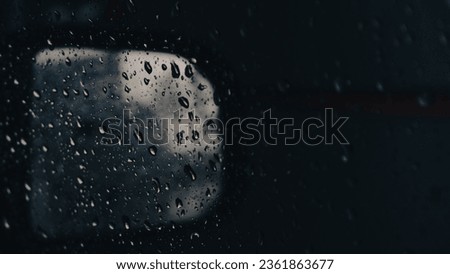 Close up of raindrops on a wet car window glass due to rain at night. Concept photo for background and for creative design.