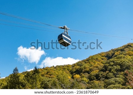 The atmosphere of the main tourist attraction Shin Hotaka in the autumn colors with a cable car and ropeway serving tourists. Japan Alps, Shinhotaka Ropeway and Fall foliage. Royalty-Free Stock Photo #2361870649