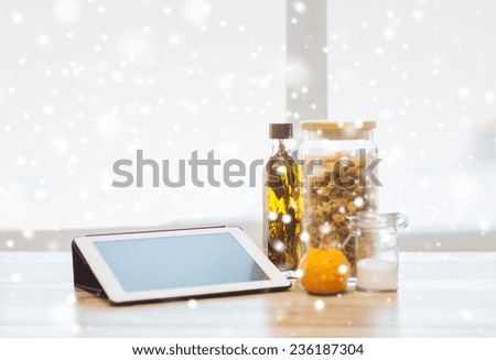 technology, food and cooking concept - close up of tablet pc computer, olive oil, pasta, salt and pumpkin on table at home