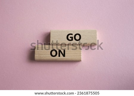 Go on symbol. Wooden blocks with words Go on. Beautiful pink background. Business and Go on concept. Copy space.