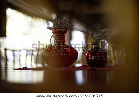 Red vases made of glass with dried plants.