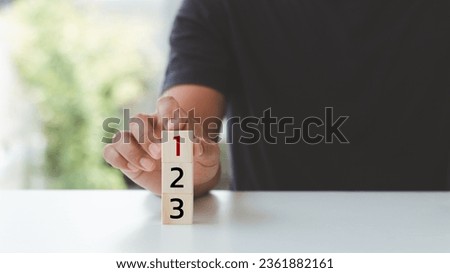 Task priority and management concept. The order of priority in any activity. Set work priorities, and arrange a to-do list. Hand arranging wooden cubes with numbers first, second, and third. Royalty-Free Stock Photo #2361882161