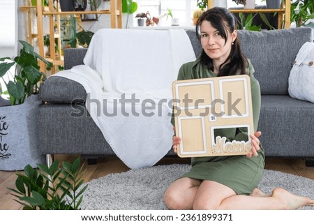 Happy woman in house holds in hands photo frame with figure at home template and key in interior. Dream house project, real estate purchase, insurance, mortgage, rent, reservation