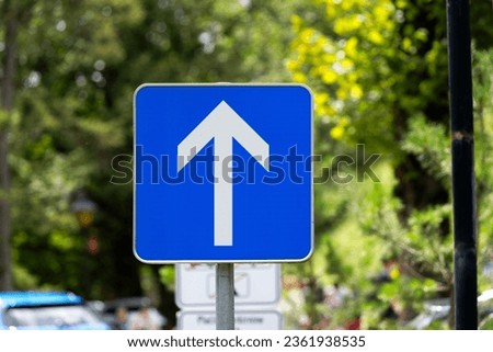 Close-up of blue and white one way road sign with arrow and car parking of castle at Slovenian City of Bled on a blue cloudy summer day. Photo taken August 8th, 2023, Bled, Slovenia. Royalty-Free Stock Photo #2361938535