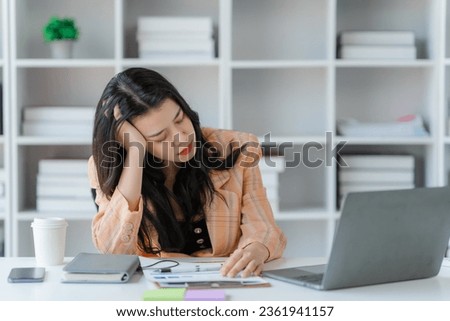 Confident young Asian business woman sitting with arms crossed smiling looking at camera in the office