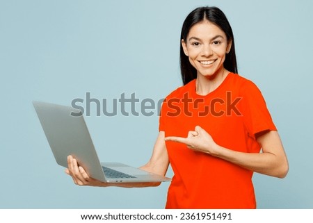 Side view young happy IT latin woman she wear orange red t-shirt casual clothes hold use work point on laptop pc computer isolated on plain pastel light blue cyan background studio. Lifestyle concept Royalty-Free Stock Photo #2361951491