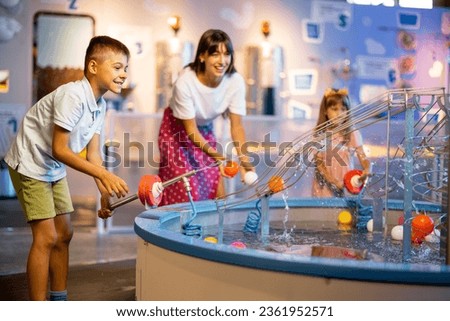 Mom with kids play with balls, learning physical phenomena in an interesting way, having fun in a science museum with interactive models Royalty-Free Stock Photo #2361952571