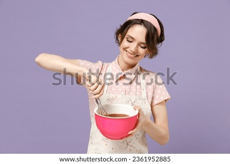 Young smiling happy cheerful housewife housekeeper chef cook baker woman wear pink apron beating egg yolks whites isolated on pastel violet background studio portrait Cooking food process concept.