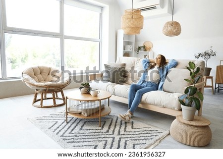 Young woman sitting on couch in living room Royalty-Free Stock Photo #2361956327