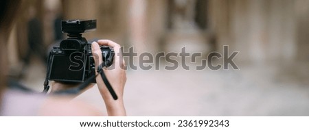 Close-up of a professional camera in female hands. Woman photographer is working on shooting, focusing, looking for a card, taking a photo