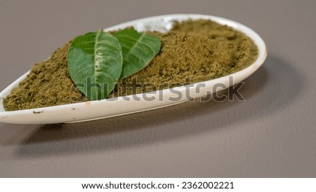 Henna Leaves and Powder in Ceramic Bowl on gray background.
