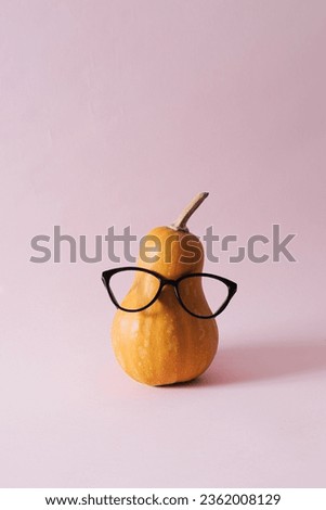 Creative funny autumn background with orange pumpkin with glasses against a pink pastel background. Minimal Halloween, autumn, thanksgiving concept.