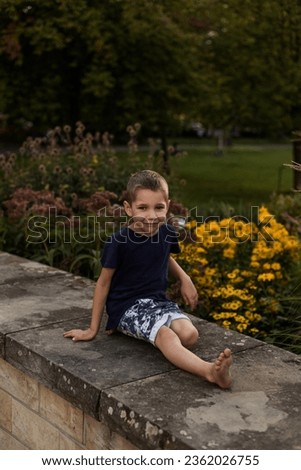 A boy plays near flowers in the park. Children's entertainment during the summer holidays. High quality photo