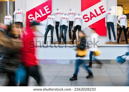 People walking through the window display with text SALE.