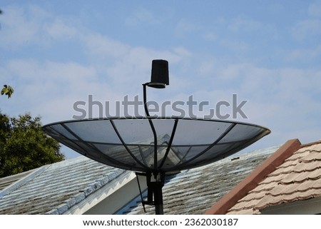 Parabola above the building with a plain sky background. A satellite dish is useful for catching television signals