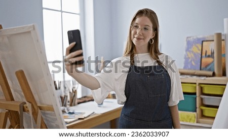 Young blonde woman artist make selfie by smartphone smiling at art studio